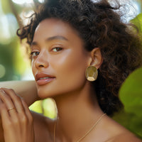 Model wearing bold Kenneth Jay Lane gold nugget clip-on earrings in sculptural form