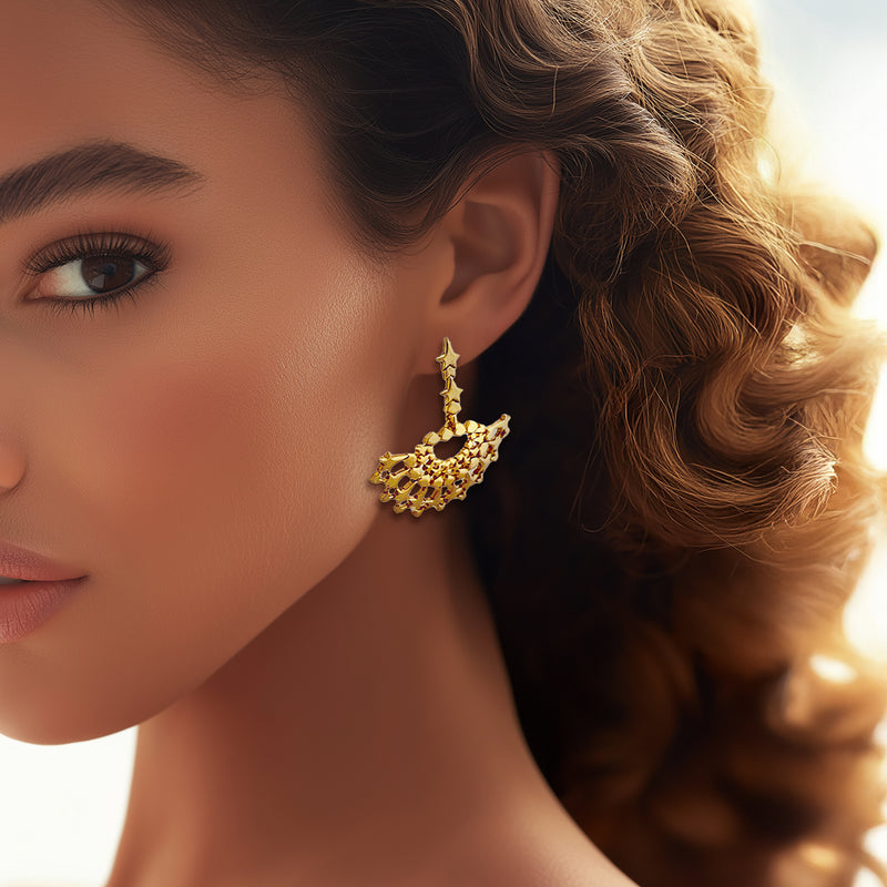 Model wearing Oscar de la Renta gold fan earrings, displaying the luminous design and starry details against a soft, elegant look.