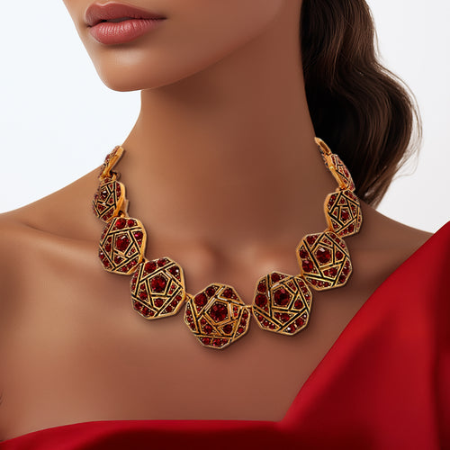 A close-up of Oscar de la Renta's geometric mosaic necklace featuring Red Siam Austrian crystals set in antique gold-plated frames, styled with a red dress for a bold statement look.