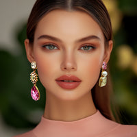 Model wearing Oscar de la Renta asymmetrical earrings, showcasing their vibrant rose crystals, luminous pearls, and elegant antique gold finish.