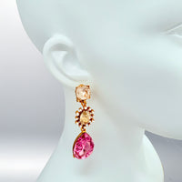 Close-up of Oscar de la Renta asymmetrical clip-on earrings featuring rose and light rose Austrian crystals with pearl accents, set in antique gold plating