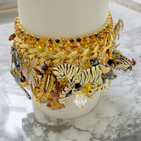 The Lunch at The Ritz Jungle Safari Bracelet displayed on a mannequin hand, highlighting its luxurious 22K gold finish and bold, whimsical charm design.