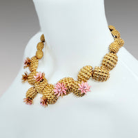 Side profile showcasing the Oscar de la Renta necklace's bold design with antique gold texture and enamel blossoms.