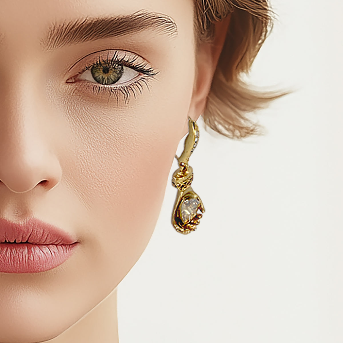 Model wearing Oscar de la Renta gold-plated glove earrings, styled with soft makeup for a sophisticated look.